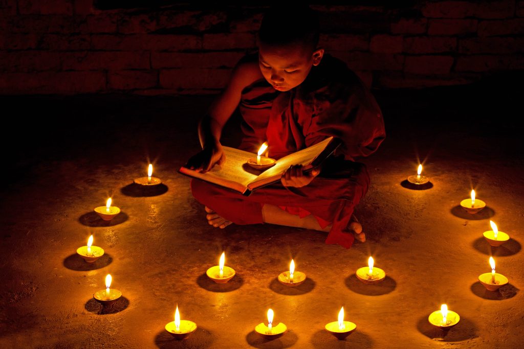 Person sitzt in einem Kerzenkreis und liest ein Buch 